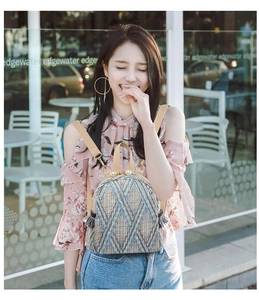 Detail of a woven mini backpack with pearl accents and tassels against an outdoor cafe