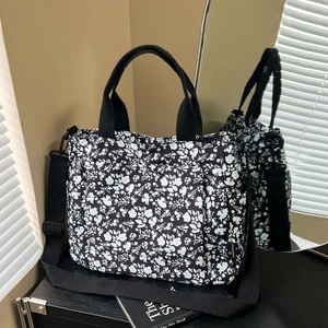 Floral canvas tote bag with black strap and adjustable shoulder strap in mirror reflection