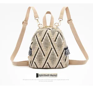Detail of woven straw mini backpack in light khaki with pearl charm and fringe