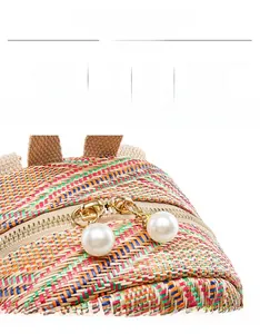 Detail of colorful woven straw bag with oversized pearl zipper pulls and gold hardware