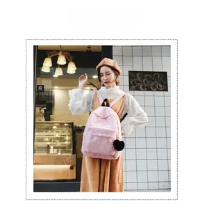 Detailed view of pink plush backpack with soft faux fur texture and black heart pendant
