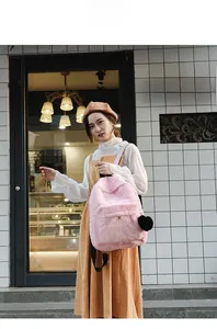 Outdoor model shot of a soft pink plush backpack featuring a black heart charm pendant