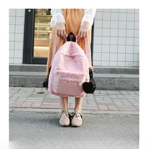 Pink plush faux fur backpack with black heart pendant shown in a soft street setting
