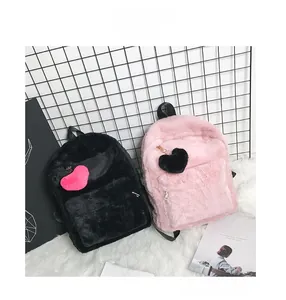 Detail of plush faux fur backpacks in black and pink with heart-shaped pendants