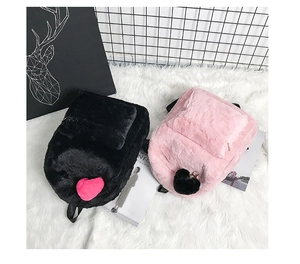 Detail view of plush backpacks in pink and black featuring fuzzy heart-shaped pom-pom charms