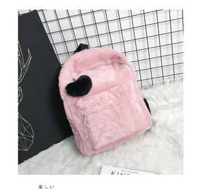 Close-up of fluffy pink faux fur backpack featuring a black plush heart charm and gold zipper