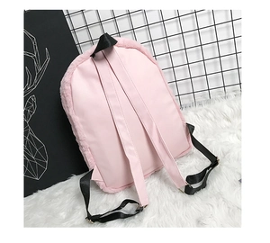 Detailed back view of pink plush backpack showing faux leather straps and metal buckles