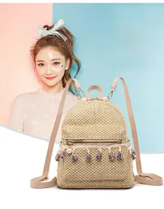 Detail of hand-woven straw backpack featuring colorful tassels and white pearl ornaments