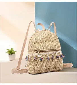 Detail of straw woven backpack featuring pearl zipper charm and colorful tassel trim