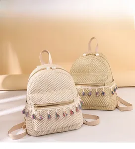 Close-up of woven straw backpack with colorful tassel fringe and pearl zipper charms