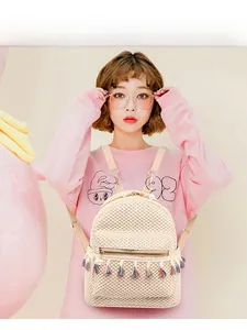Detailed view of women's mini straw backpack featuring colorful tassels and pearl charms