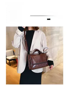 Close-up of brown faux leather Boston bag with silver rivet studs and a side zipper