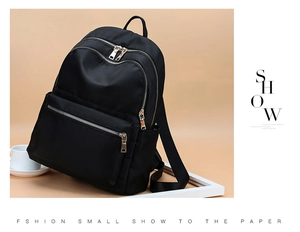 Détail du sac à dos noir imperméable en nylon avec fermetures éclair dorées et poches