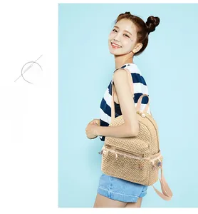 Detail of straw backpack featuring colorful tassel charm and elegant pearl zipper pull