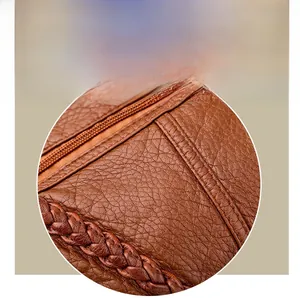 Detail of brown litchi leather crossbody bag with metal zipper and braided strap