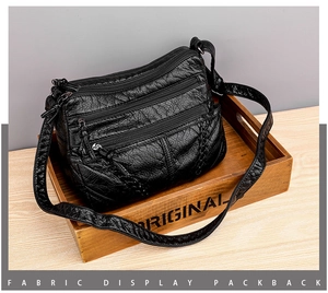 Detail view of black vintage textured leather crossbody bag with multiple zipper pockets
