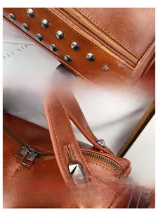 Close-up of caramel leather handbag with metal rivet decor and reinforced stitching