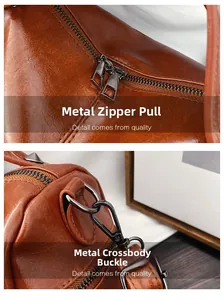 Detail of gun-metal zippers and shoulder strap hooks on a brown leather Boston bag