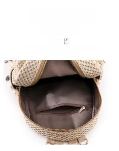 Detail view of woven straw backpack interior with zipper pocket and colorful tassel charm