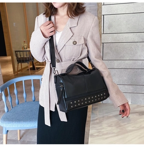 Detail of black matte leather Boston bag featuring dual-row silver rivet base and shoulder strap