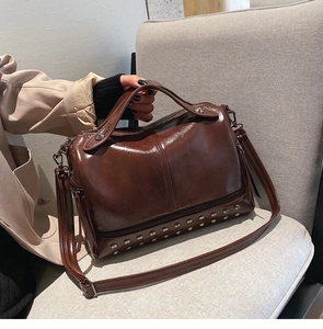 Detail of dark brown vintage faux leather boston bag with silver rivets on the bottom
