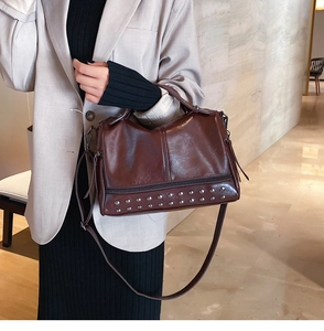 Detail view of a vintage dark brown leather boston bag with metallic rivet decorations