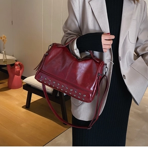 Detail view of burgundy leather boston bag with silver punk rivets on the bottom