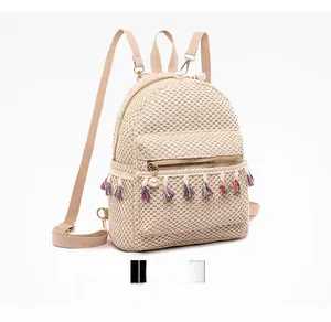 Detail of cream straw backpack featuring colorful fringe tassels and pearl zipper pull