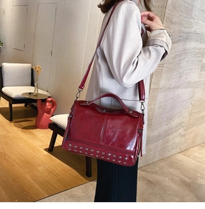 Detail of red leather Boston bag featuring silver studs and detachable shoulder strap