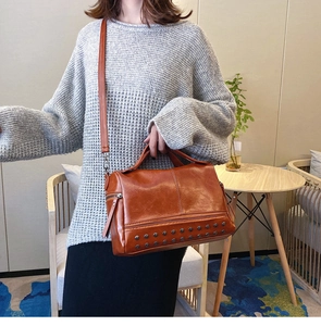 Detail view of brown vintage Boston bag with metallic rivets and adjustable strap