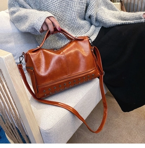 Detail of caramel brown Boston bag with vintage rivets and adjustable shoulder strap