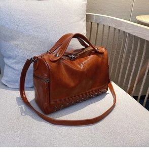 Detail of brown faux leather Boston bag with metallic rivets and decorative stitching