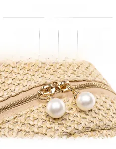 Close-up of woven straw texture with gold zipper and elegant pearl puller detail