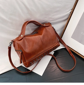 Detailed view of brown vintage leather Boston bag with metallic rivet embellishments