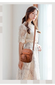 Detailed view of brown soft leather crossbody bag with multiple zipper pockets on a model