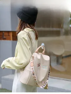 Damenrucksack aus beigem Oxford-Gewebe mit Blumenstickerei und gemusterten Trägern im Freien