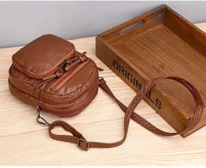 Detailed view of brown lychee texture leather crossbody bag with multiple zippers