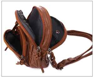Macro side view of caramel brown crossbody bag with three zipper compartments and lining