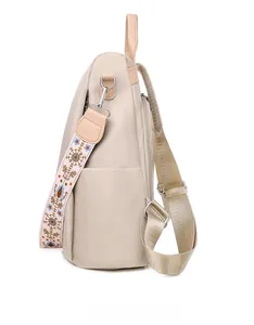 Seitenansicht des beigen Nylonrucksacks mit Blumenstickerei-Gurt und Lederakzenten