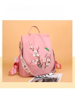 Dettaglio ravvicinato dello zaino in nylon rosa con ricami floreali e uccelli tradizionali