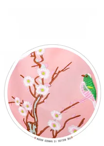 Dettaglio del tessuto ricamato rosa con uccello verde e motivo floreale di prugno bianco
