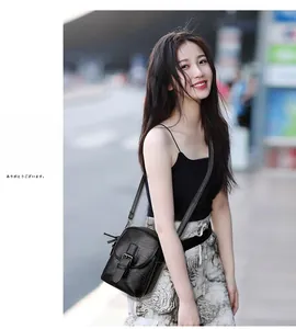 Street style view of a black textured soft leather crossbody mobile phone bag with flap