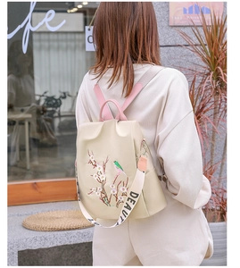 Scatto esterno di uno zaino beige con ricami floreali e tracolla decorativa Beauty