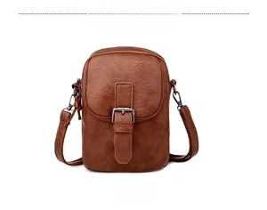 Front detail of vintage brown leather phone bag with dual zippers and decorative buckle