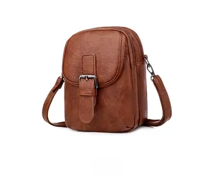 Side view of brown crossbody phone bag featuring pebbled faux leather and metal buckle
