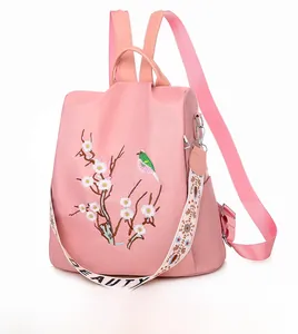 Dettaglio zaino in nylon rosa con ricami floreali e tracolla decorativa fantasia