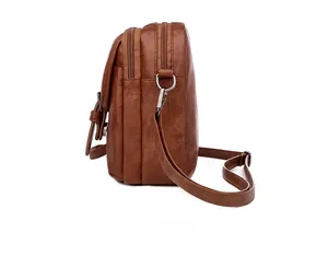 Detailed side view of brown multi-compartment crossbody bag with zippers and front pocket