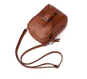 Detailed view of brown PU leather crossbody bag with flap pocket and dual zipper main compartment