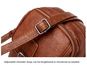 Detail of adjustable strap and litchi texture on brown crossbody bag with dual zippers