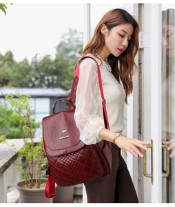 Side view of woman wearing burgundy quilted leather backpack with kangaroo logo detail